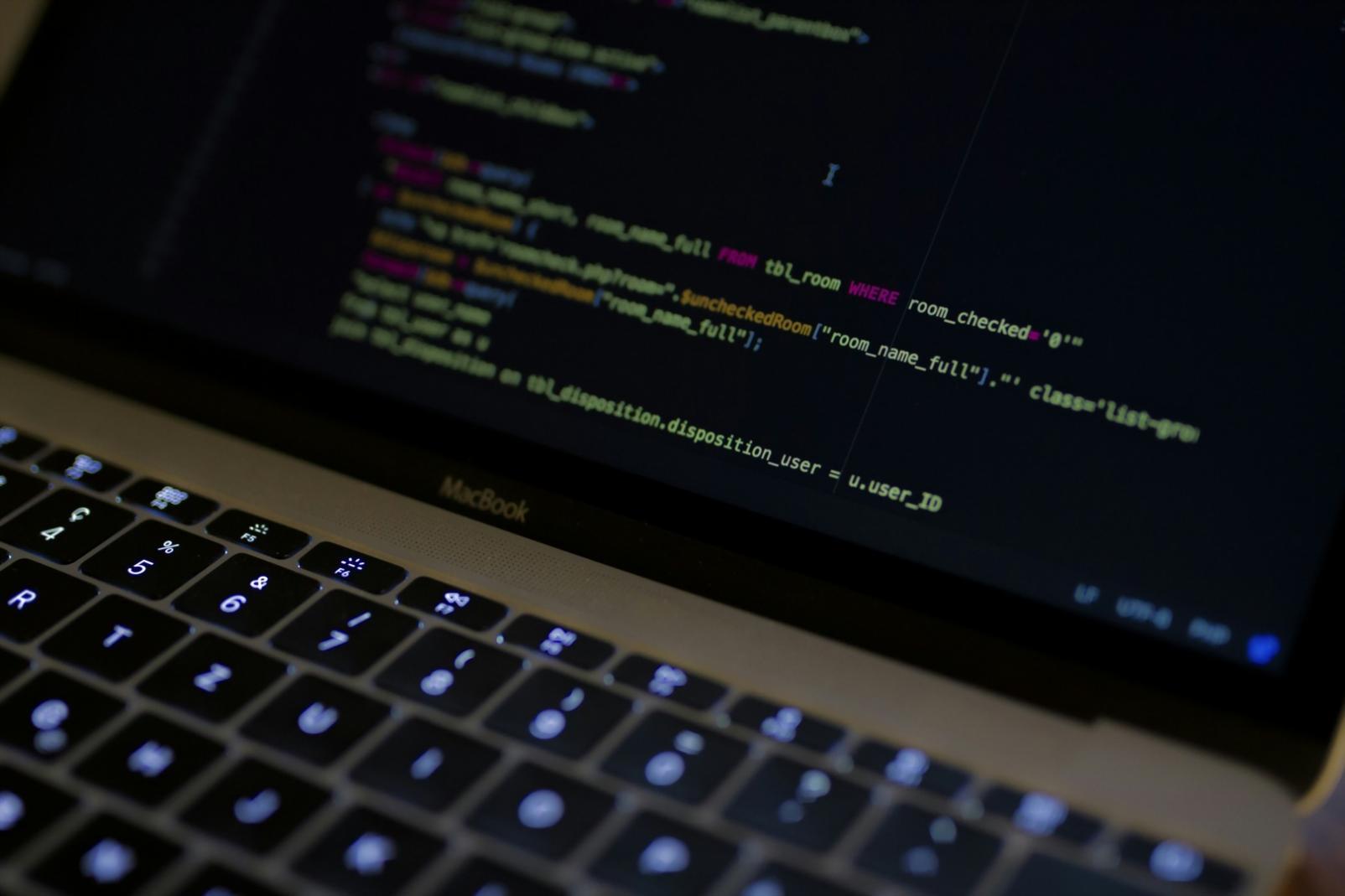 Mesa de trabajo con iPhone mostrando juego en desarrollo y código Swift en MacBook